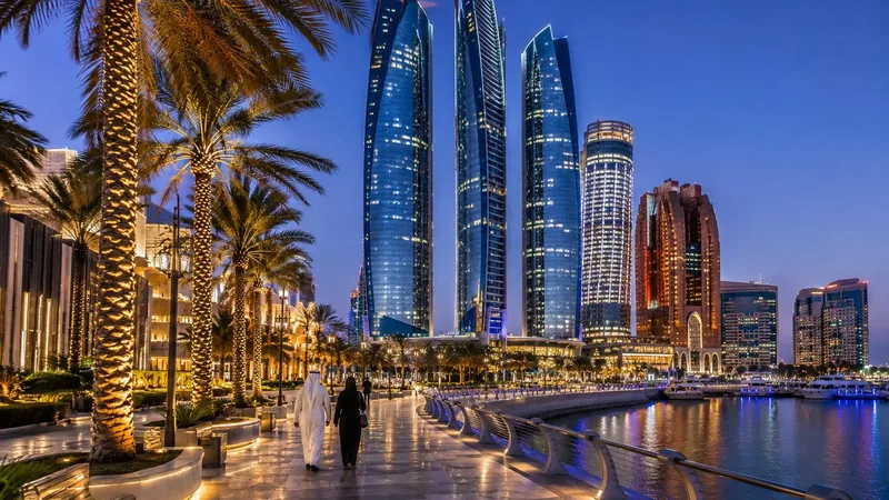 Вечерняя набережная Абу-Даби: пальмы в подсветке, небоскрёбы Etihad Towers, пара в национальной одежде у воды