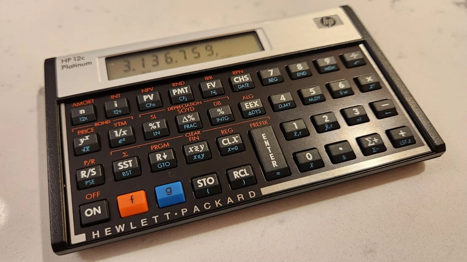 HP 12c Platinum financial calculator on a desk, the display showing 3,136.759