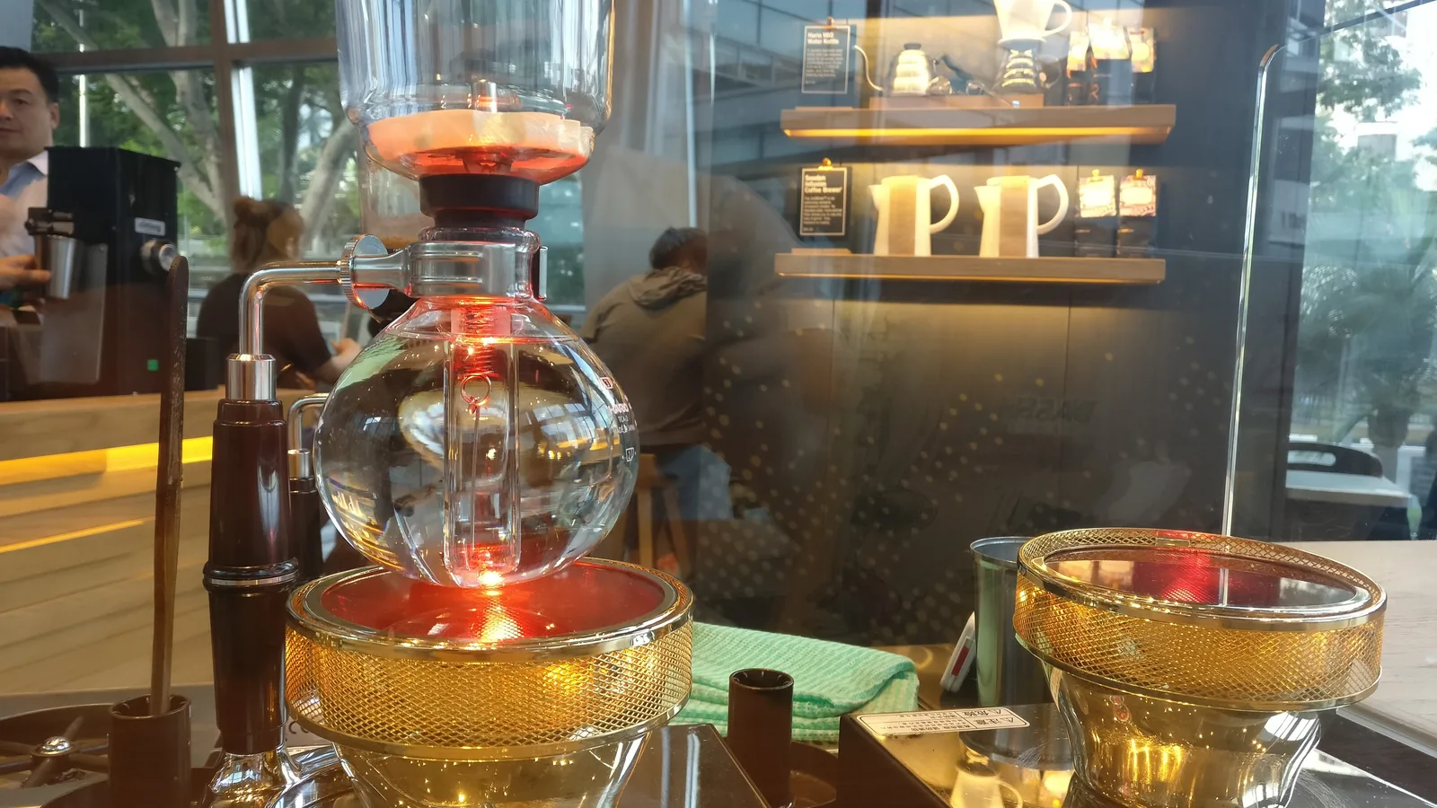 A siphon coffee brewer on a bar counter inside a cafe
