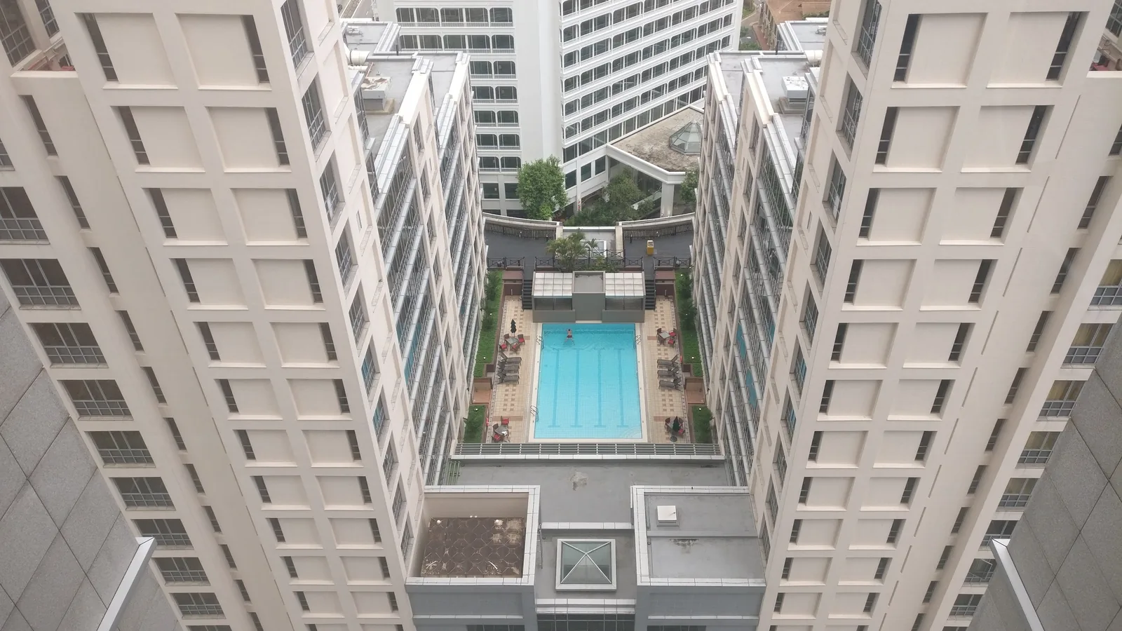 A view down between two white apartment towers to a swimming pool below