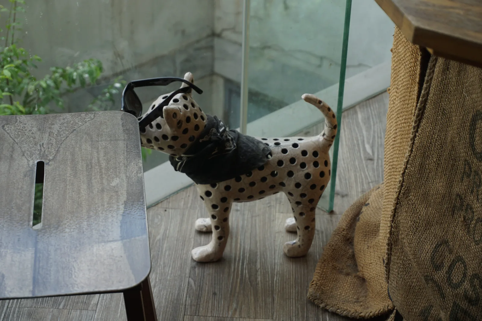 A ceramic dalmatian figurine on a table next to a jute coffee sack