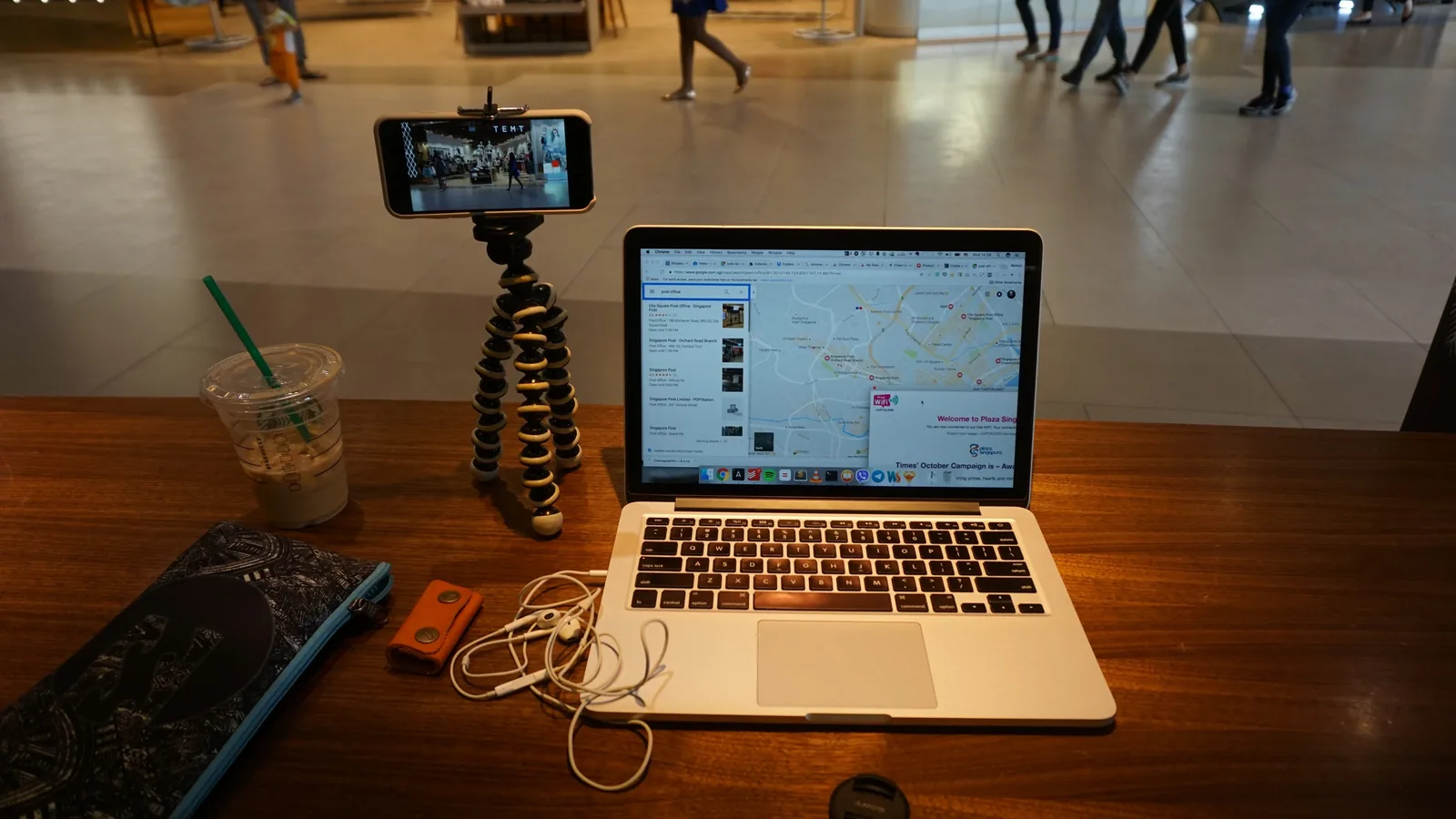 A phone on a tripod filming a laptop on a cafe table