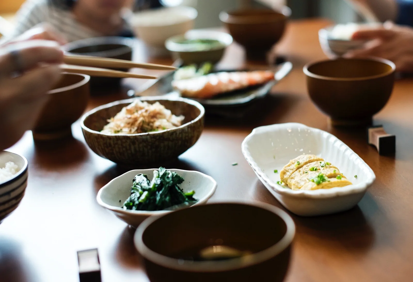 A shared table of Japanese dishes seen from above, several people eating